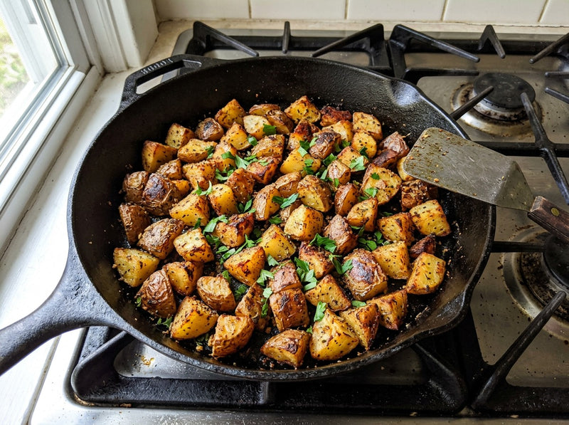 Crispy golden breakfast potatoes with peppers and onions in a cast iron skillet